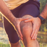 A hiker experiencing knee pain while on a hiking trail